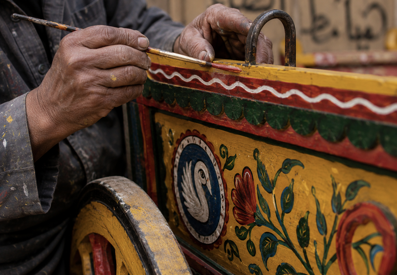 An artisan hand-painting a traditional Egyptian cart with colorful floral and bird motifs